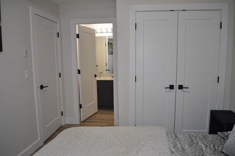 A bedroom with a bed, a mirror, and a dresser at The Laurent at Laurel Apartments, Edmonton, T6T 2T5